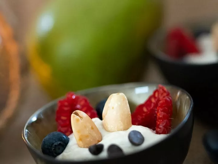 Gros plan sur la crème de cajou et poires garnie de fruits rouges et d'amandes, sur une toile de jute