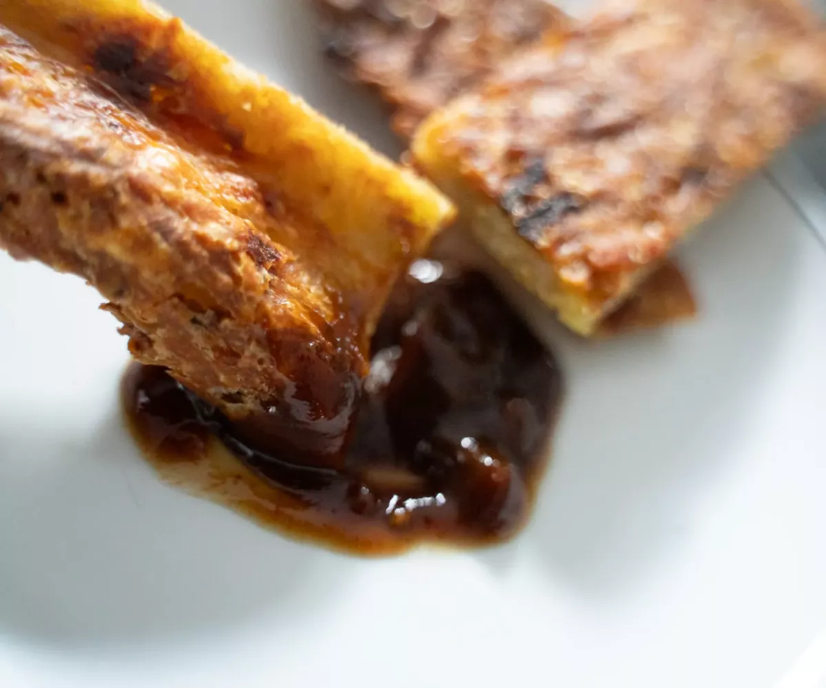 Morceau de crousti-galette de pommes de terre doré et croustillant trempé dans une sauce brune