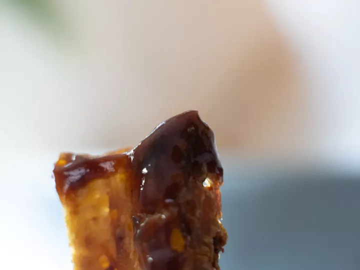 Morceau de crousti-galette de pommes de terre trempé dans une sauce foncée