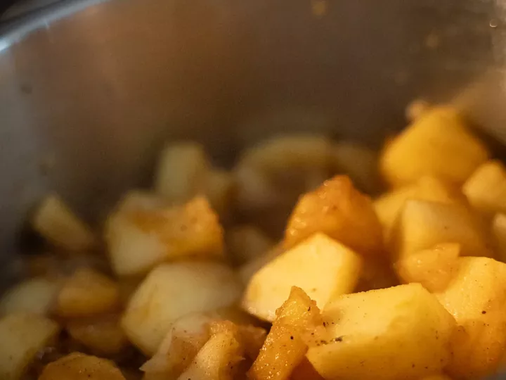 Dés de pommes et de poires caramélisés à la cannelle dans une casserole en inox