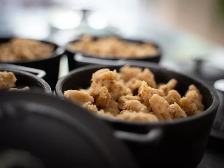Plusieurs mini-cocottes en fonte garnies de crumble, prêtes à enfourner