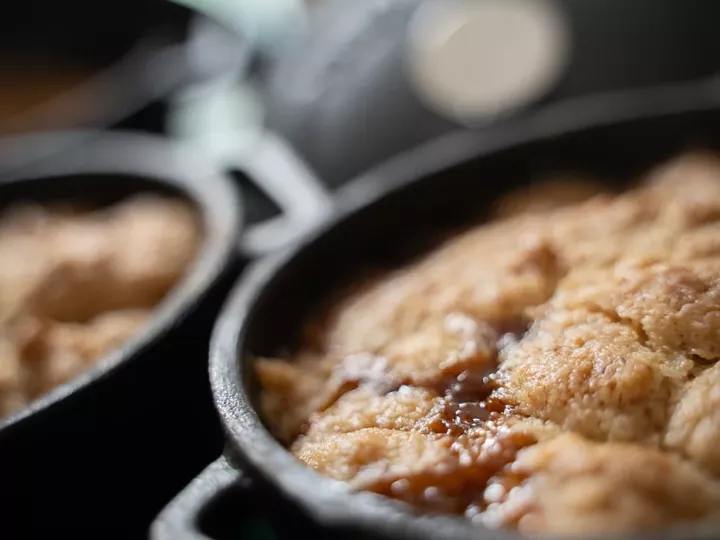 Mini-cocotte en fonte à la sortie du four, crumble doré et jus de fruits caramélisé