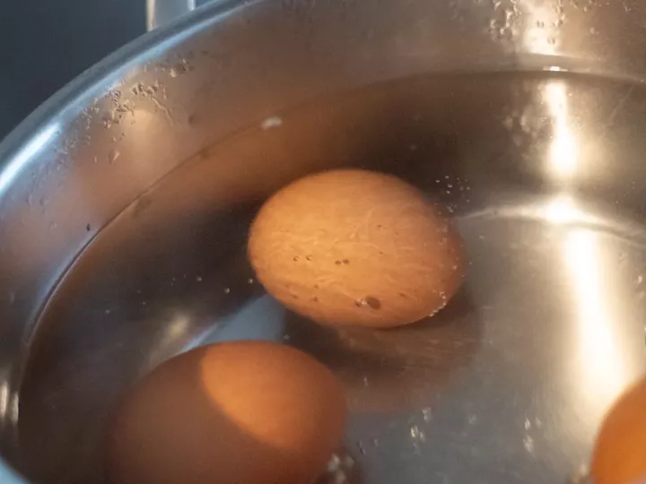 Œufs bruns plongés dans l'eau bouillante d'une casserole en inox