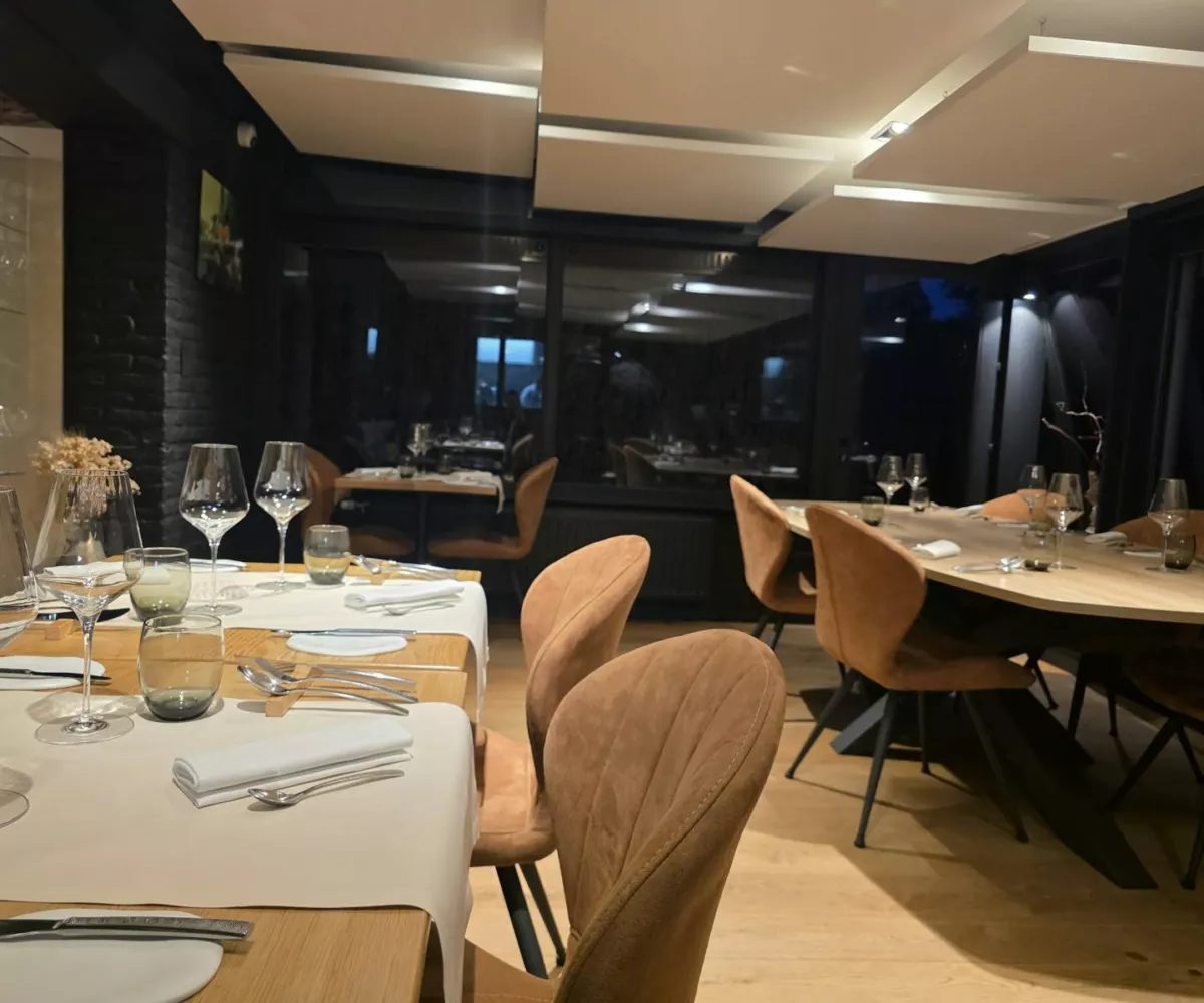 La salle du restaurant Luma à Nalinnes, avec ses tables en bois, ses chaises cuir et ses baies vitrées