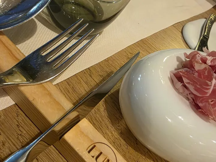 Mise en bouche à partager : fines tranches de charcuterie dans un galet de porcelaine blanche, chez Luma