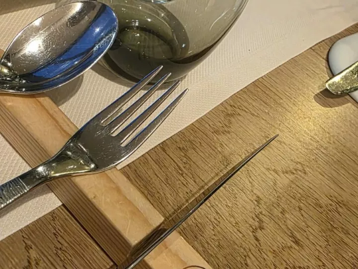 Couverts posés sur un porte-couverts en bois gravé au nom de Luma