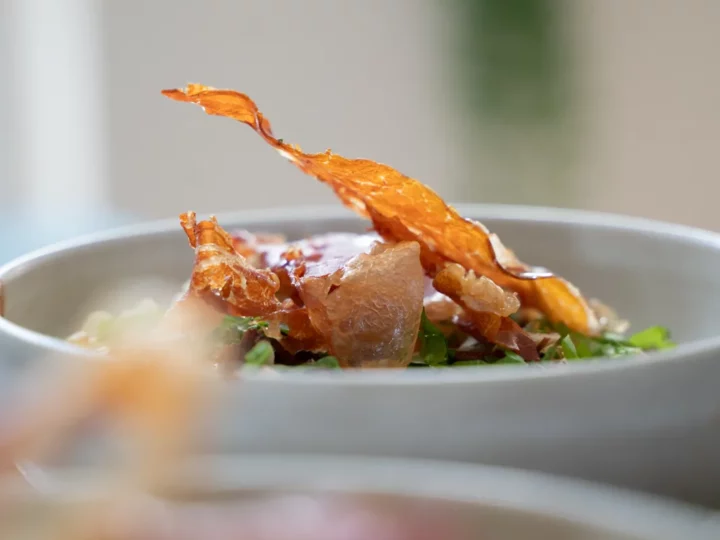 Chips de serrano en équilibre sur un bol de risotto de céleri rave