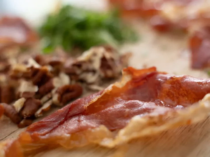 Chips de jambon serrano, noix de pécan concassées et livèche ciselée sur une planche