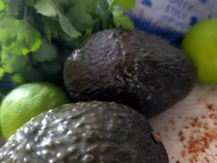 Deux avocats, citron vert, botte de coriandre et pot de yaourt grec au lait de brebis, ingrédients de la sauce verte