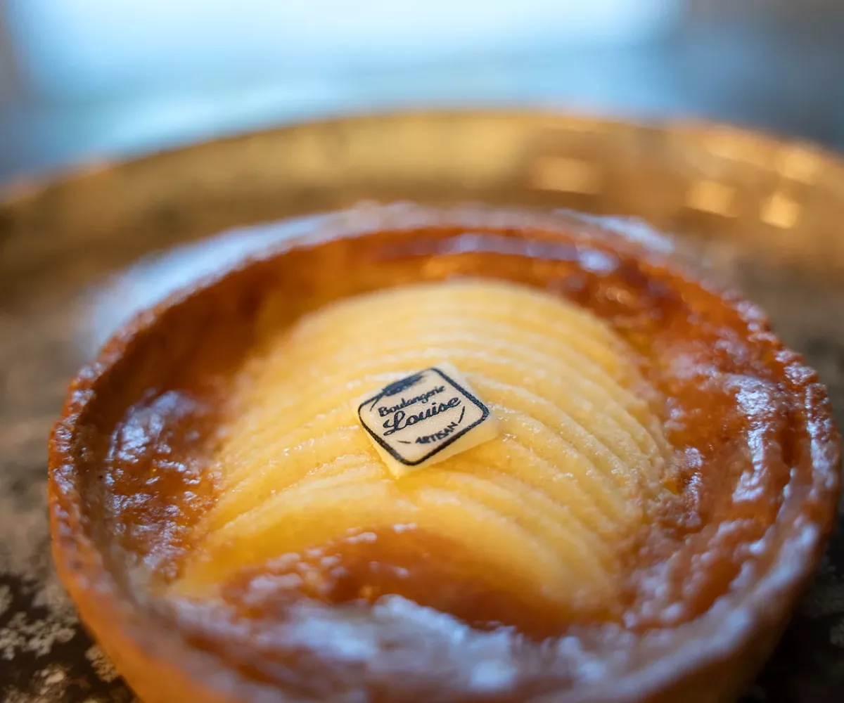 Tartelette normande aux pommes de la Boulangerie Louise, pommes en éventail et logo de la boulangerie sur le dessus