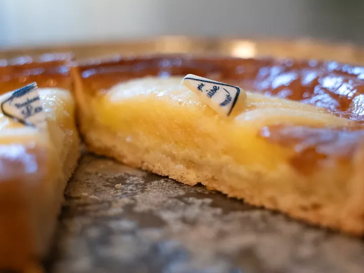Part de tartelette normande aux pommes en coupe, croûte dorée et crème jaune sous les pommes